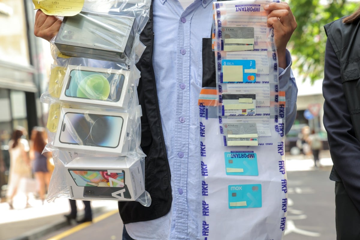 A Hong Kong police officer holds up seized evidence on May 3, relating to the arrest of 100 people over cyber fraud, including a love scam in which a victim in Canada lost HK$23 million (US$2.9 million) after falling for a swindler’s “sweet talk”. Photo: Jelly Tse